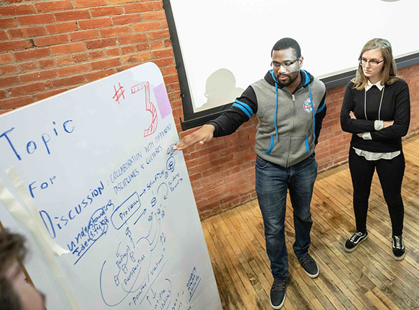 Two Design Factory members stand by a dry erase board.