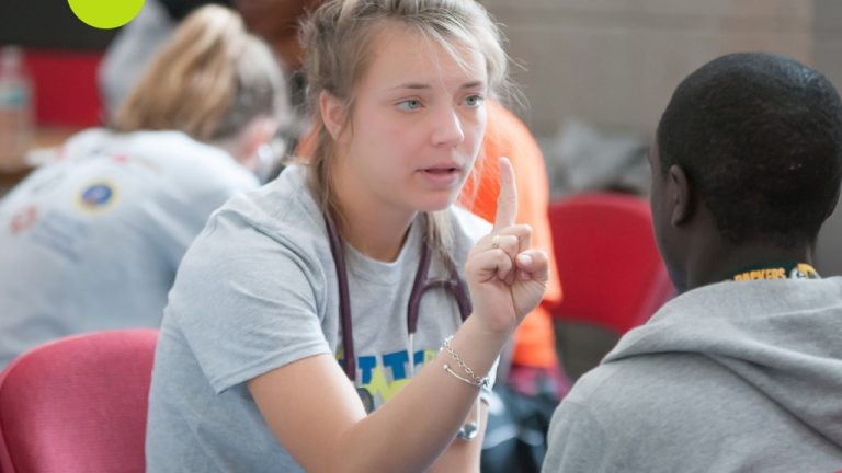Volunteer giving eye exam to student-athlete 