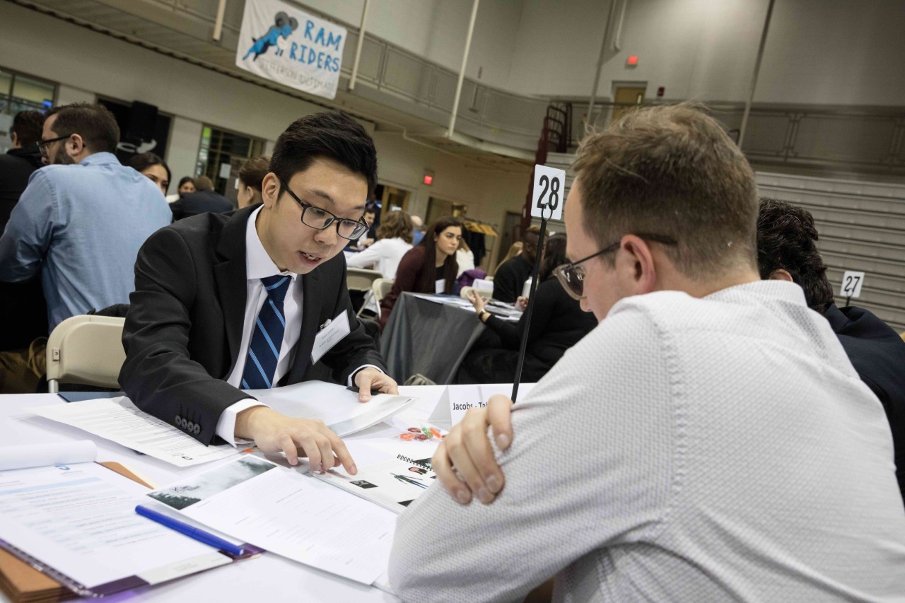 A student shows off his portfolio to an employer at Design Expo.