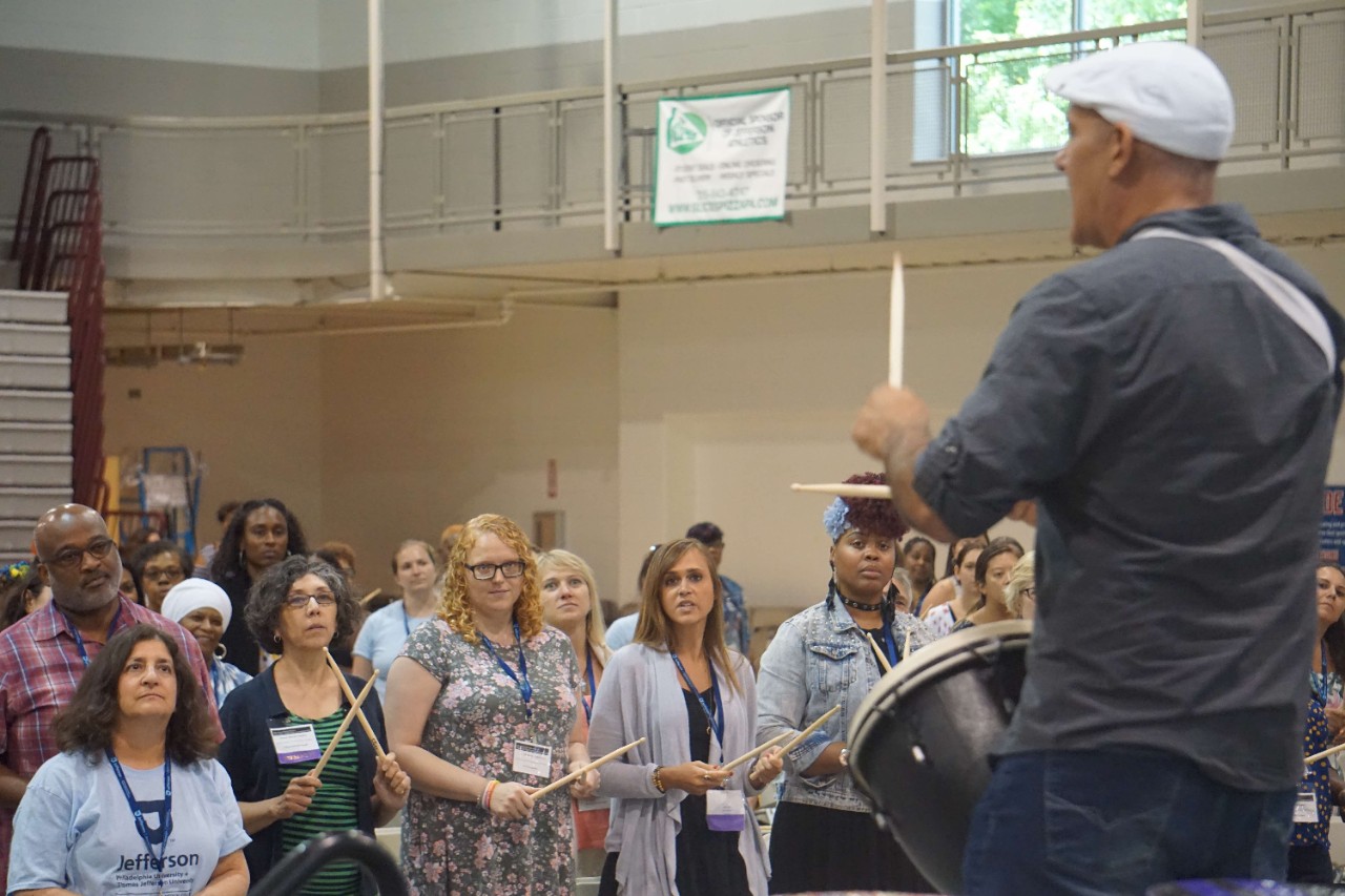 Meeting attendees practice drumming 