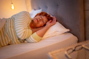 Senior woman wearing pajamas lying in bed, sleeping in bedroom