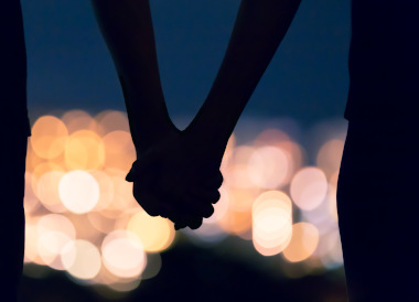 hand holding at night against blurred city lights in the background