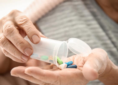 Older cancer patient looking at pills