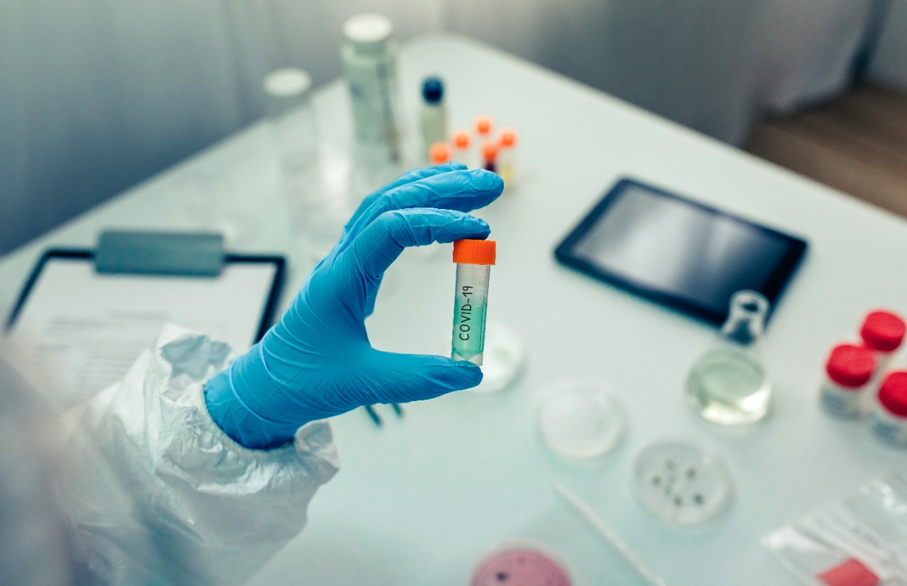 Scientist hand showing vial with vaccine in the laboratory. Selective focus on vial in foreground