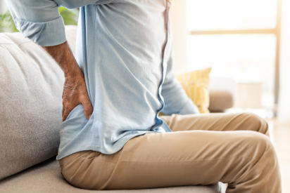 White man sitting on couch with back pain