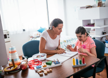 white woman working with a white woman with an intellectual disability using many props and toys.
