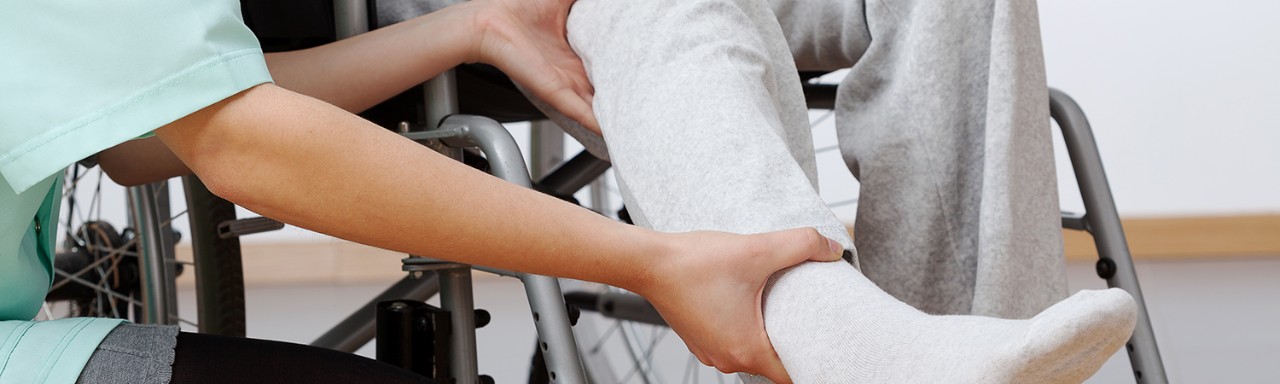 Young physiotherapist exercising with elder disabled person