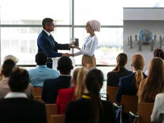 Businesswoman receiving award from businessman in a business seminar 