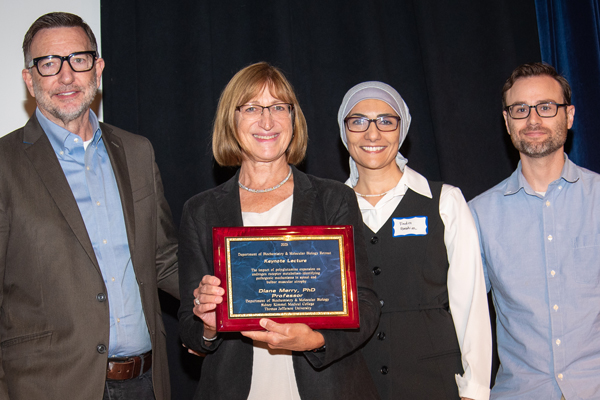 Dr. Merry (second from left) is presented with a plaque commemorating her keynote lecture by Dr. McMahon (left), and retreat organizers Dr. Fadia Ibrahim (third from left), and Dr. Michael Soniat (right)