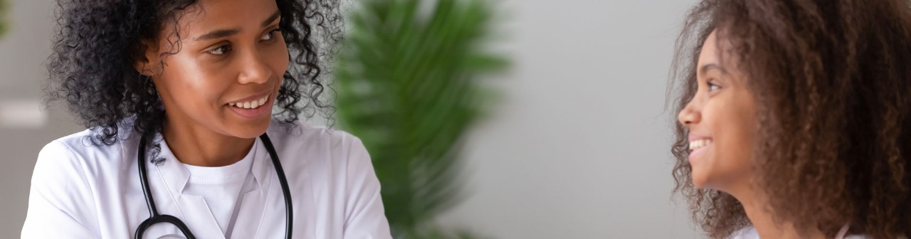 Friendly african american female doctor talking to teen girl patient