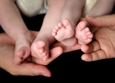 Little Baby Twins Feet in parents hands. Parenthood, family, twins, children and love concept.