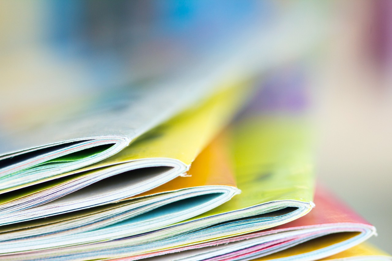 colorful-books.jpg Close up edge of colorful magazine stacking with blurry bookshelf background for publication and publishing concept , extremely DOF