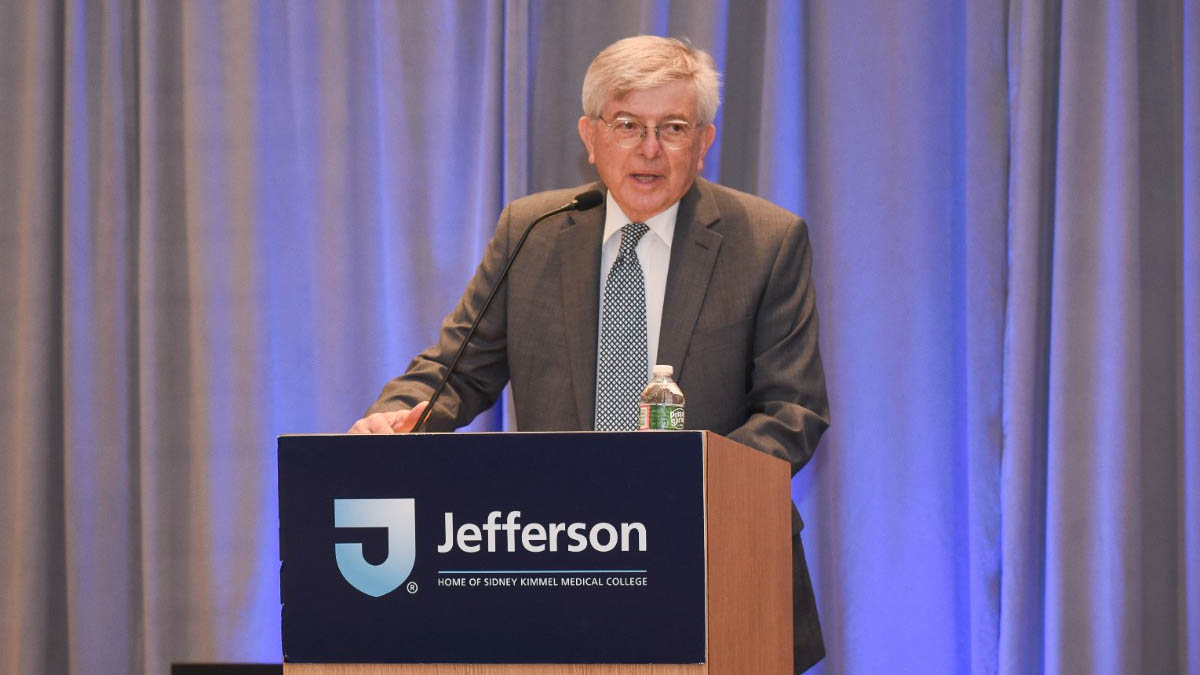 Robert M. Stein, MD ’68, FACC, FAHA speaks from a podium with a Jefferson logo on the front.