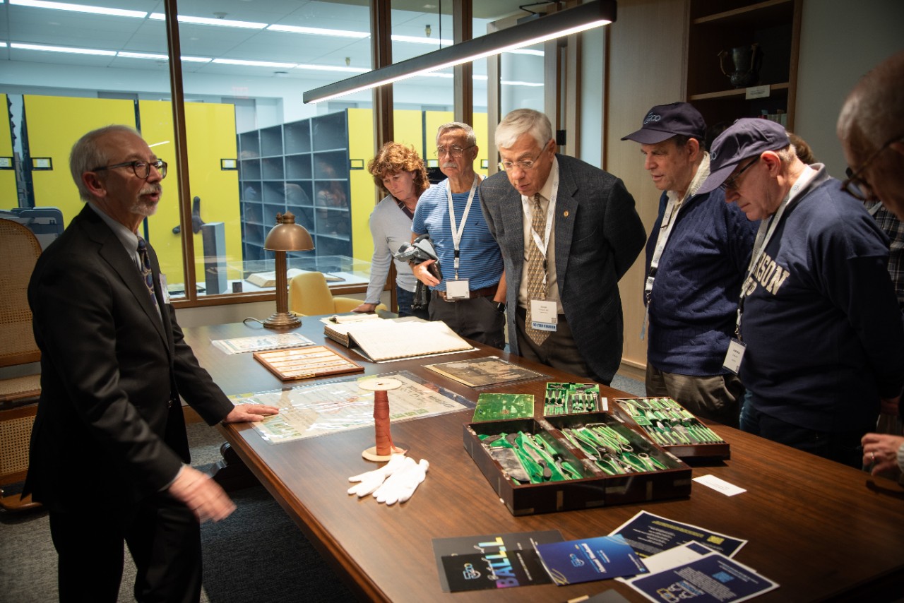 Archivist Michael Angelo discusses artifacts displayed on a table across from visitors.