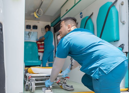 Rear view of a doctor pulling a stretcher out of an ambulance