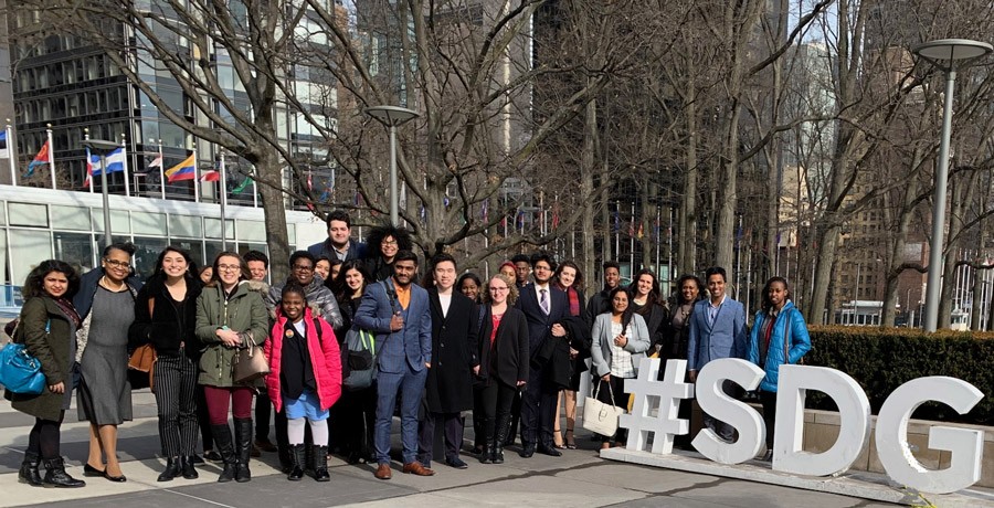 Students gathered in front of a building with an #SDG sign