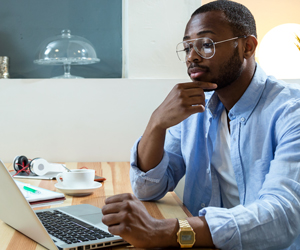 Man using laptop while sitting in a wheelchair. GOALS2 flyers lists information about how the program can help students with disabilities, including testimonials and specific areas of assistance provided. 