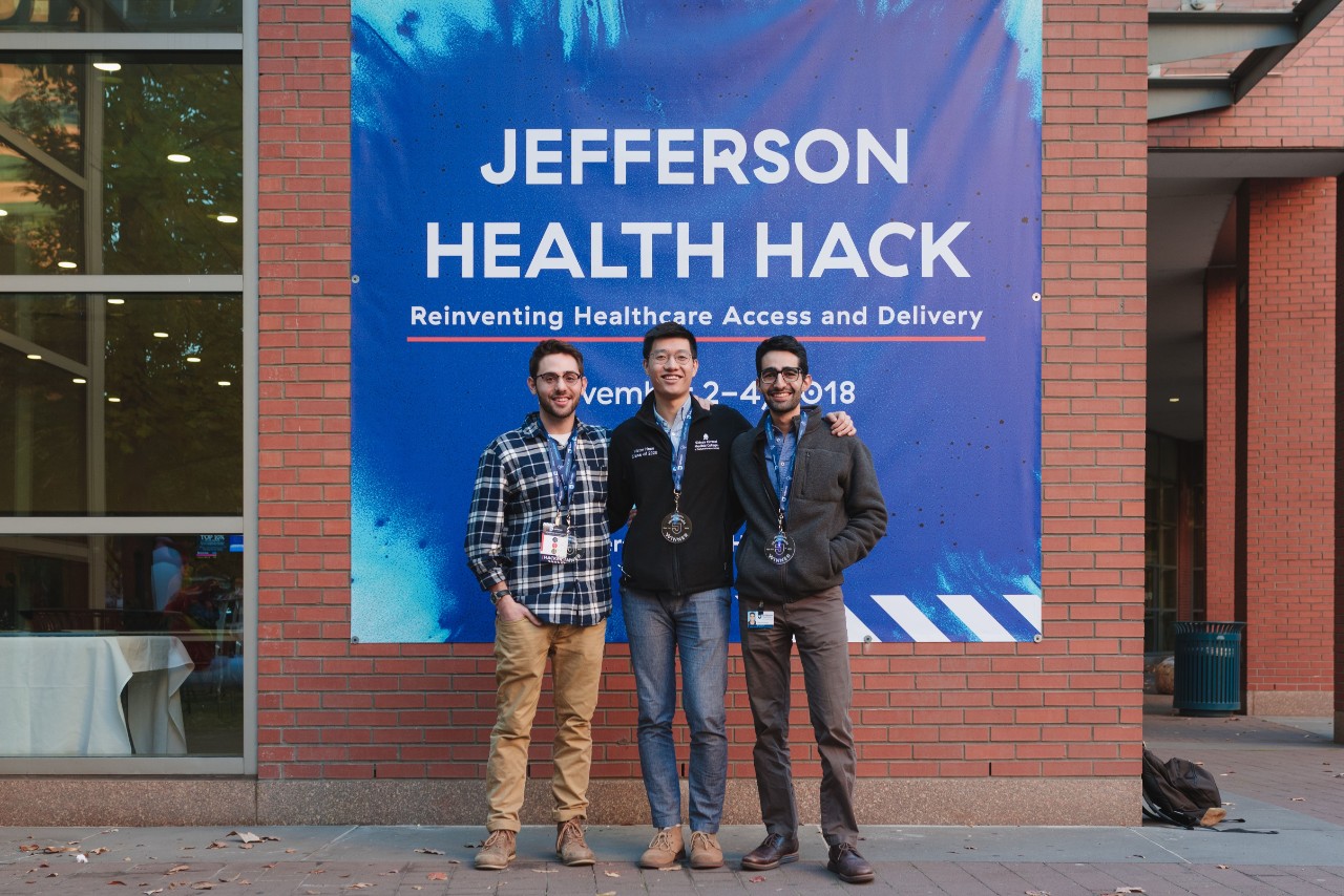 Three students in front of the Jefferson Health Hack sign