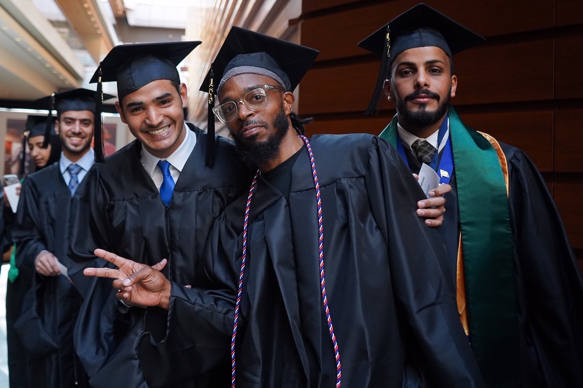 Four students in caps and gowns at graduation.