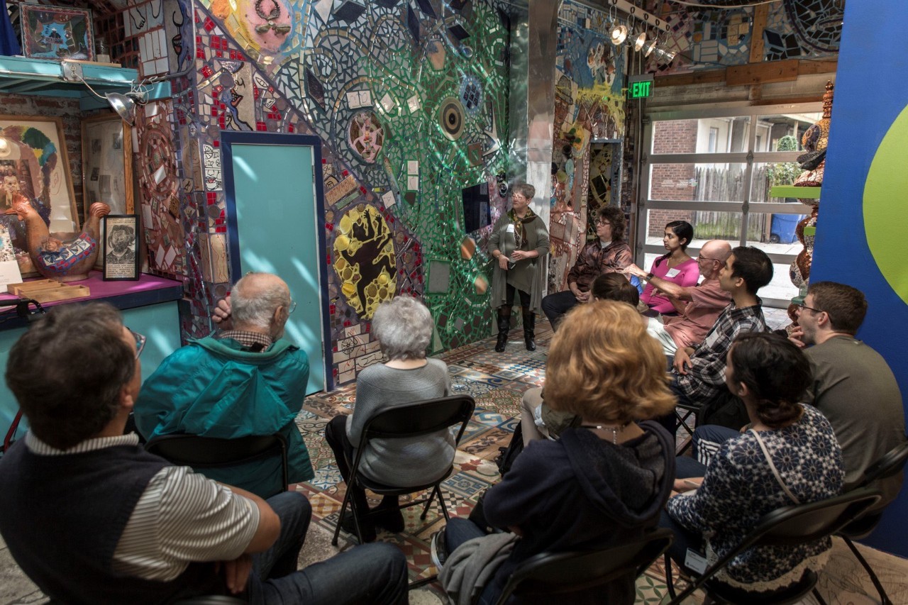 People sitting in chairs looking at a mosaic.