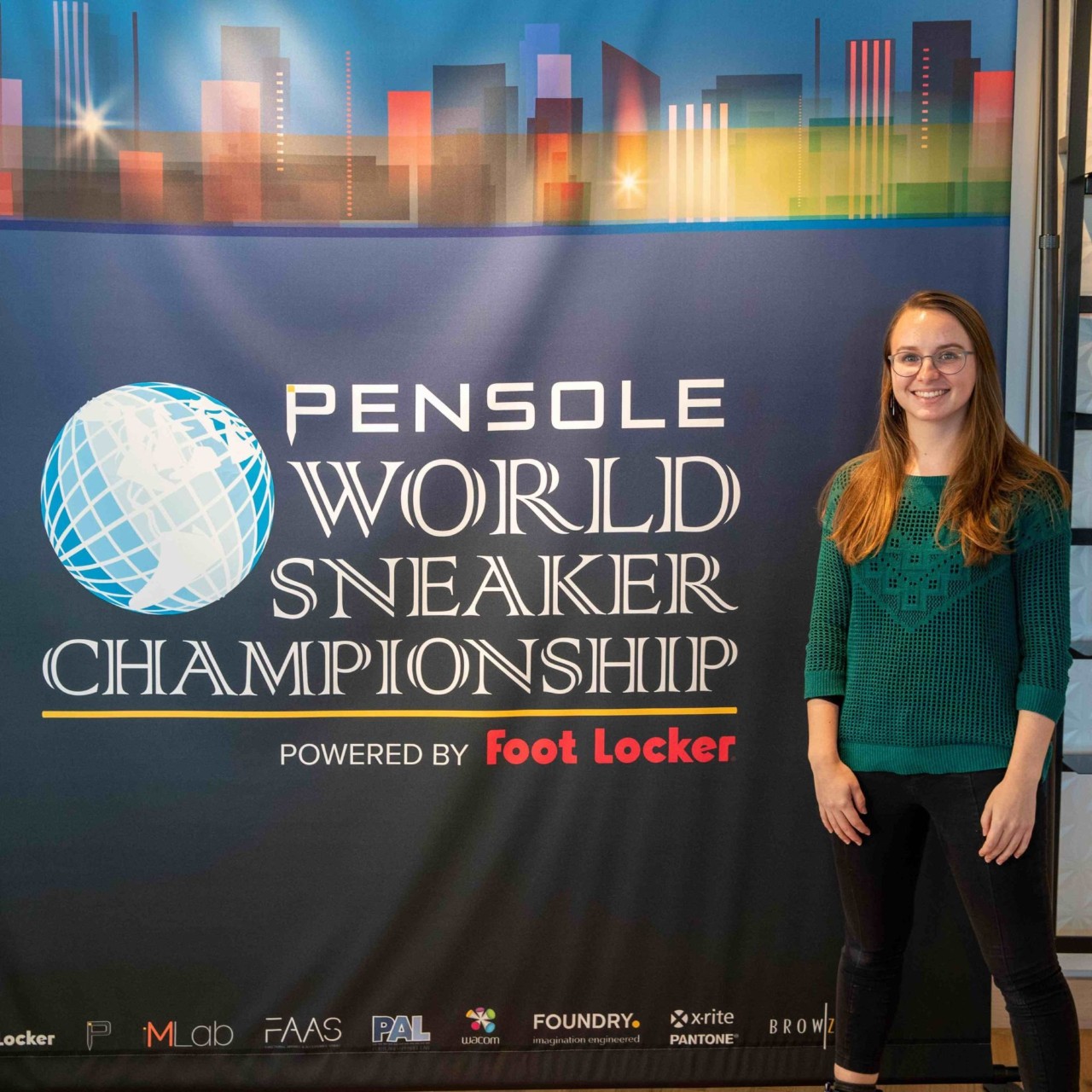 Elena Krupicka stands in front of a World Sneaker Championship Banner