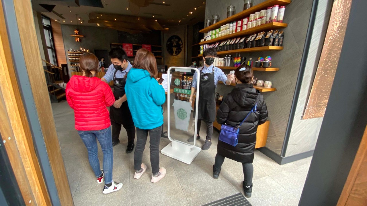 Wearing masks, people lined up for temperature checks before entering the mall.
