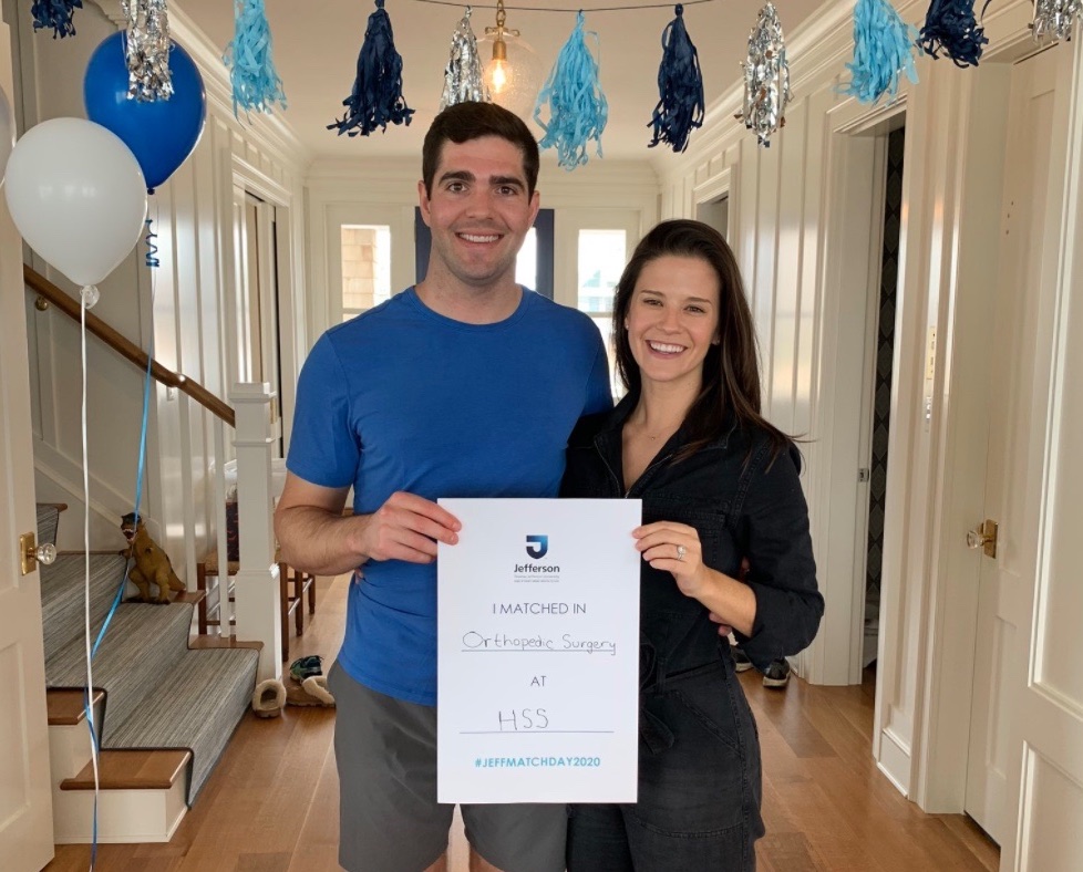 Medical student holds a match day sign with his wife