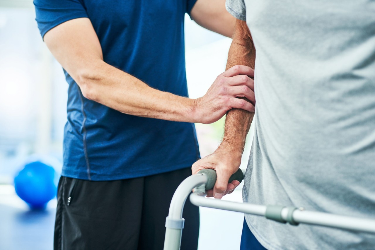 A physical therapist working with a patient Cropped shot of an unrecognizable male physiotherapist helping his senior patient to use a walker at the rehabilitation center