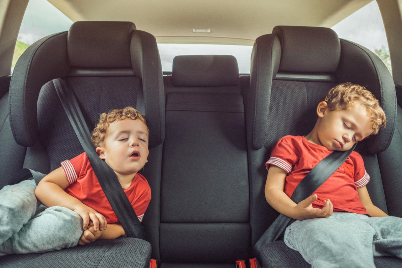 two boys rocked to sleep in the back of a car.