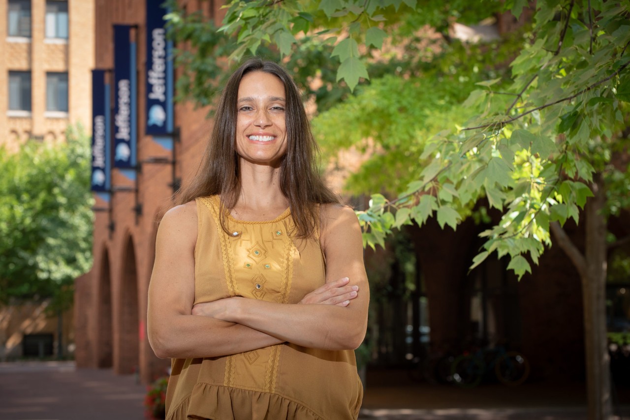 woman wearing yellow shirt standing outside, tree in background