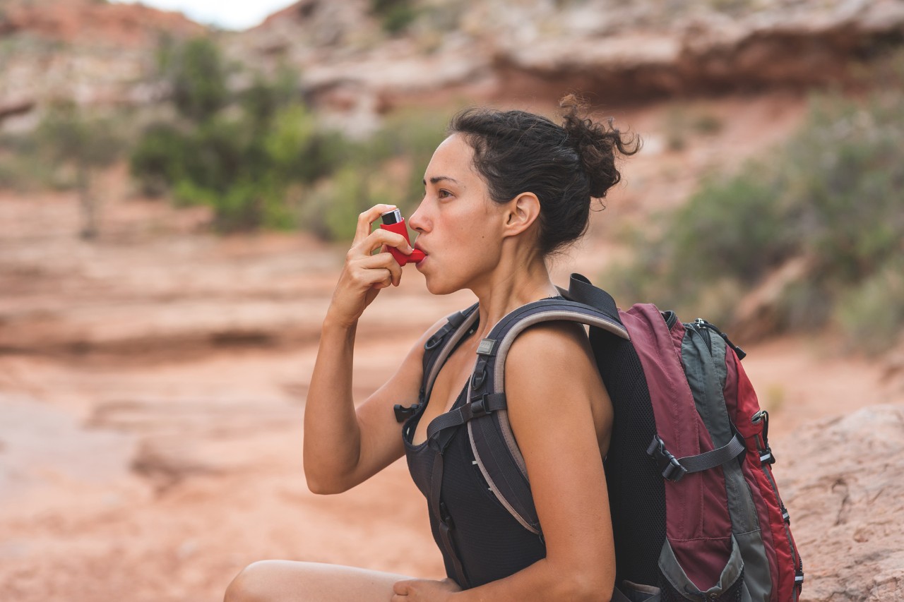 Athlete using an inhaler on a hike in the desert.