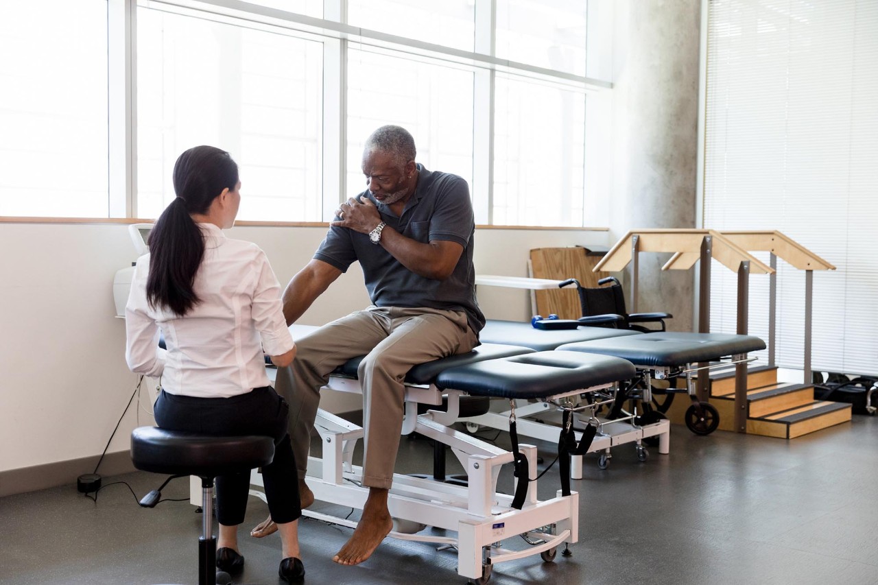 Senior man with an injured shoulder in rehab clinic