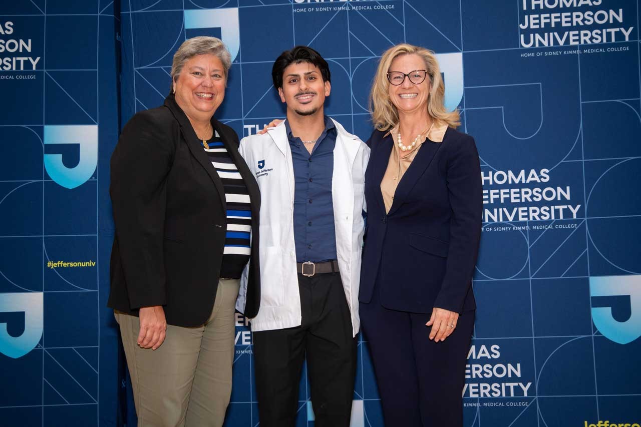 Student Karam Alsabbagh receives his white coat from Dean Dr. Mary Hess and Dr. Elena Umland