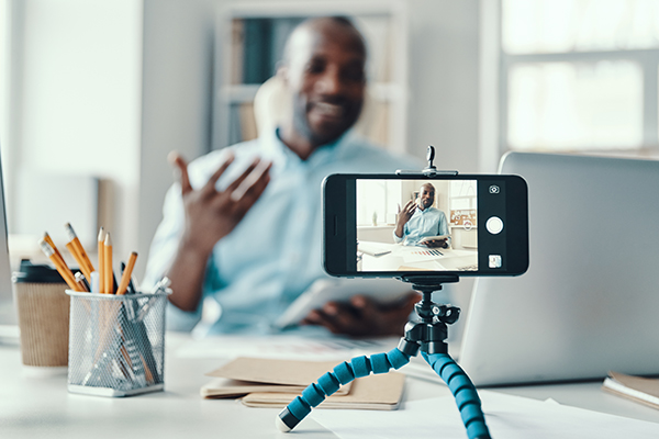 Handsome young African man in shirt telling something and smiling while making social media video         