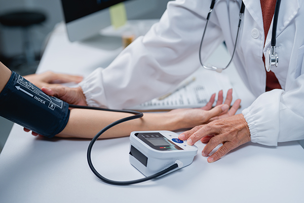 Doctor checking patient blood pressure during a medical examination, helping monitor health, prevent hypertension, and ensure wellness in a clinic setting